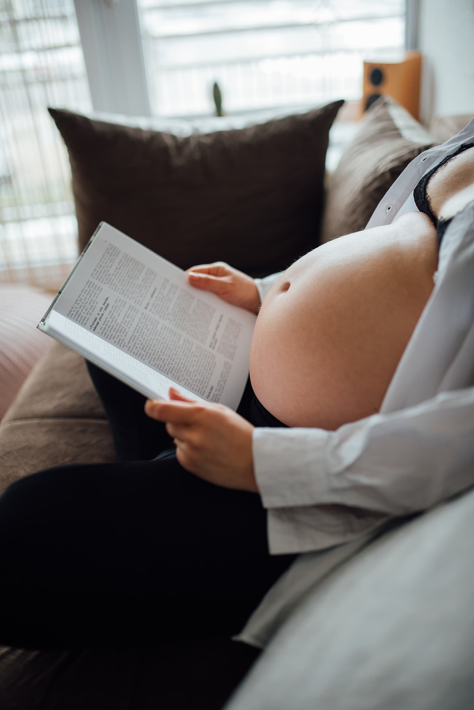 Gestante lendo um livro, sentada no sofá